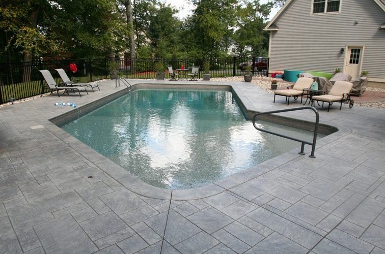 This is a photo of a Lazy L style inground swimming pool with custom pool house and furniture.