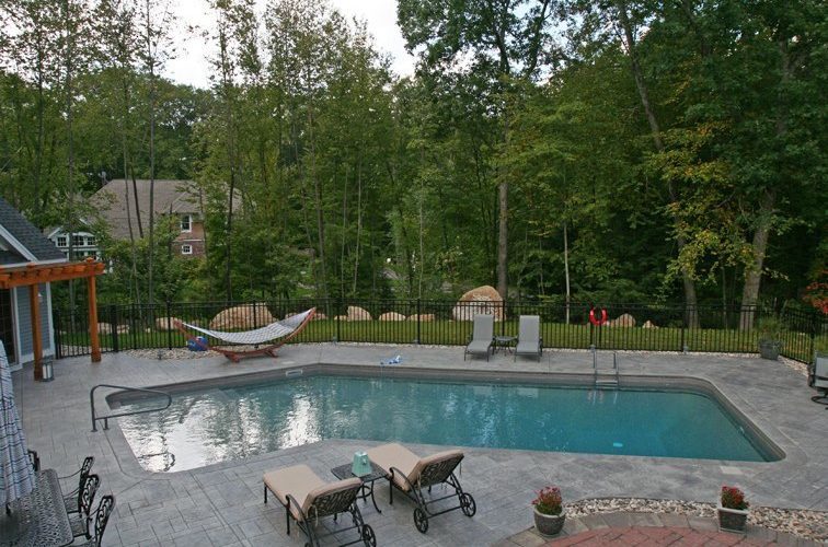 This is a photo of a Lazy L style inground swimming pool with custom pool house and furniture.