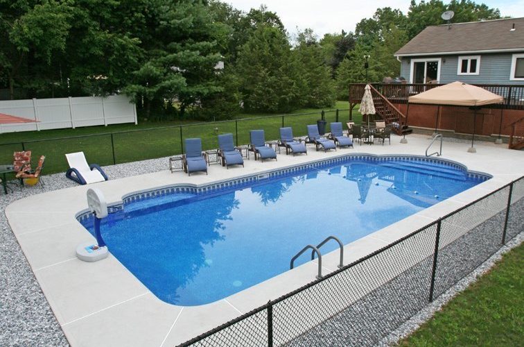 This is a photo of a patrician in ground pool with custom pool house, chairs and deck