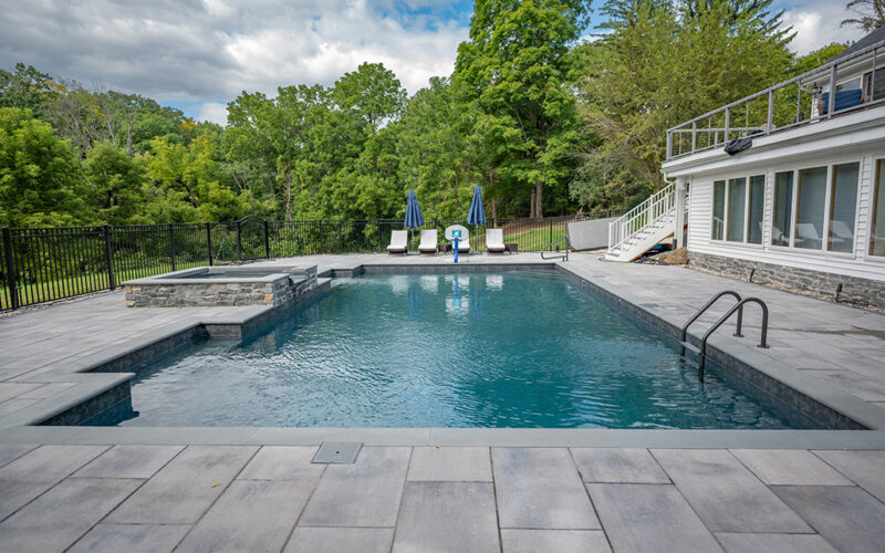 Custom Inground Pool installed by Majestic Pools with outdoor lounge chairs and hot tub
